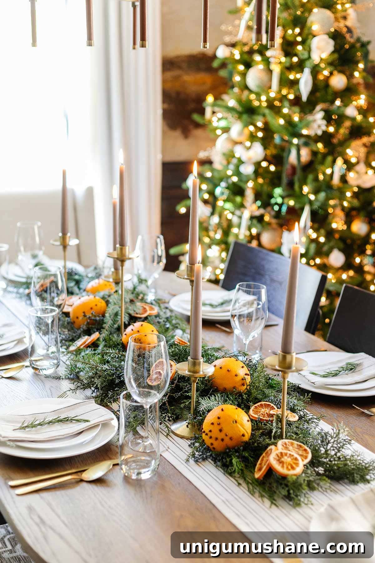 simple christmas table centerpiece using dried orange slices, orange pomanders, candle holders, and fresh evergreen branches