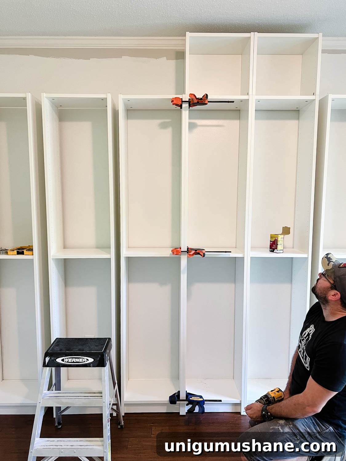 Convert IKEA Billy Bookcases into Built-In Bookshelves 11 using clamps to keep bookcases together to attach them with wood screws to make diy built in bookshelves