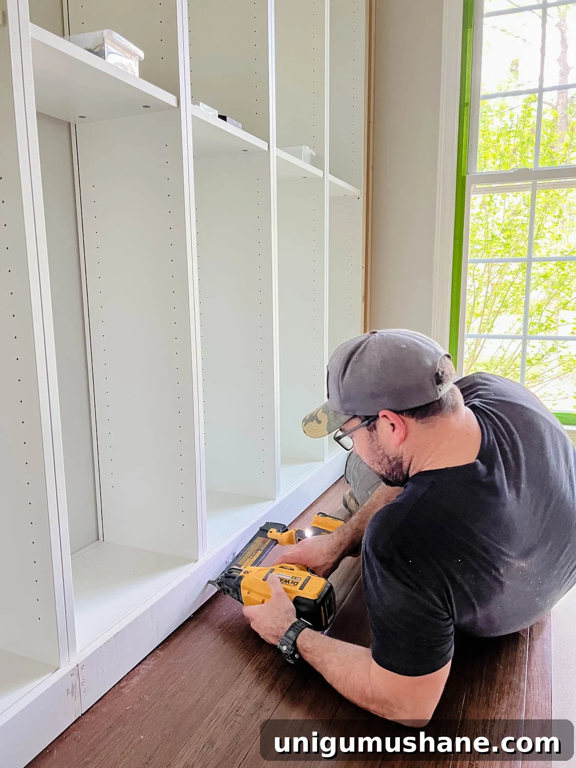 Convert IKEA Billy Bookcases into Built-In Bookshelves 18 attaching 1x4 board to the bottom of bookcases using a finish nailer for DIY built in bookshelves