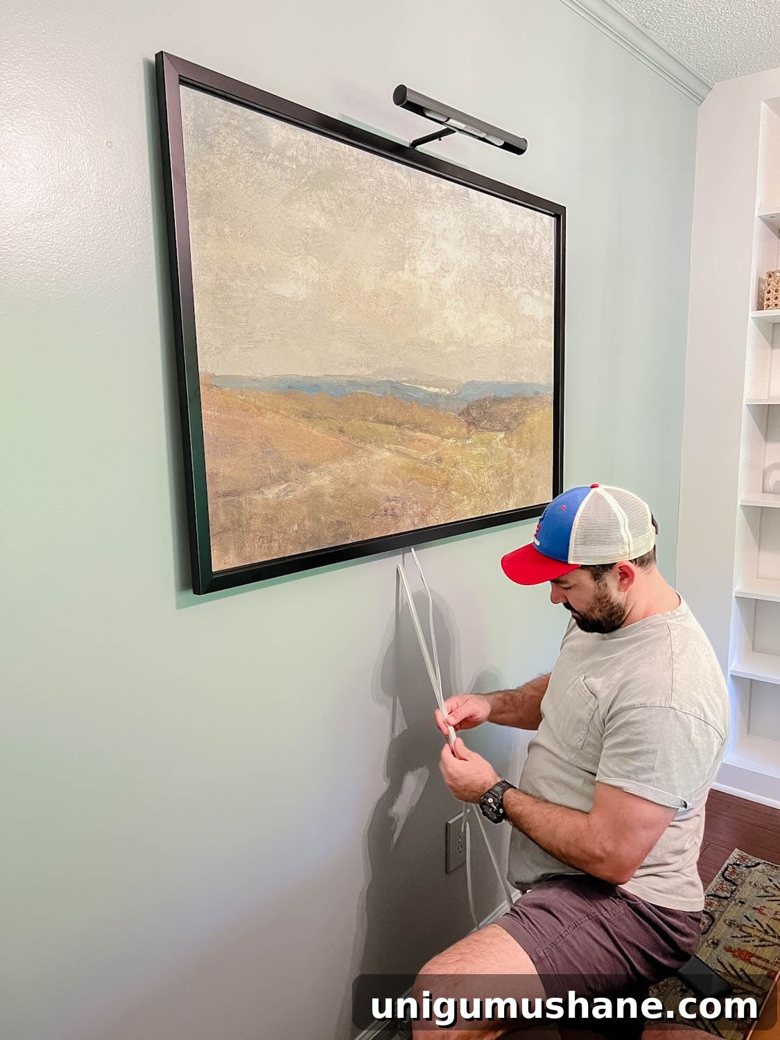 Install a Plug-In Picture Light Without Hardwiring 4 installing a picture light above a piece of art and wrapping cord in cord covers