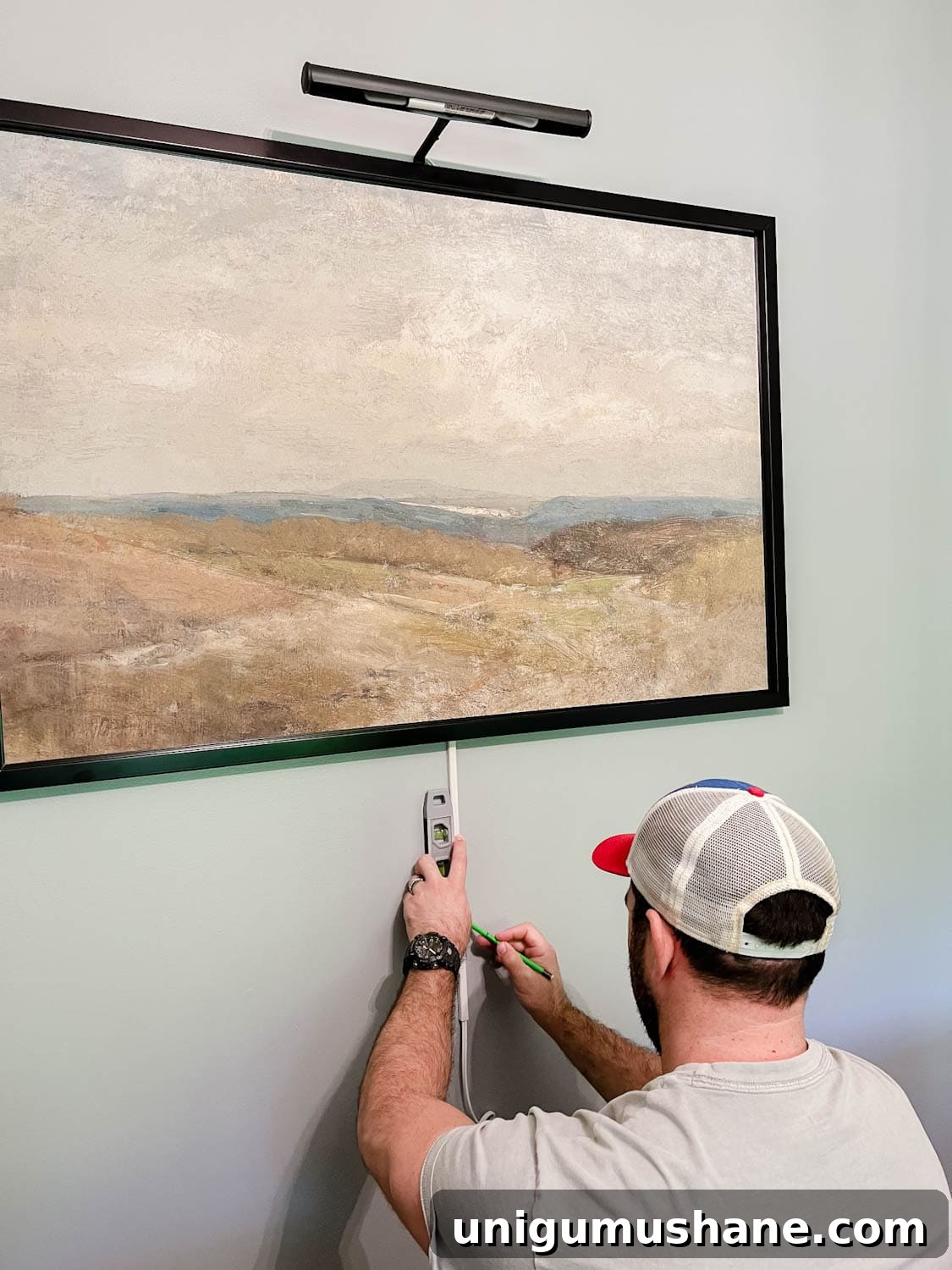 Install a Plug-In Picture Light Without Hardwiring 5 installing a picture light above a piece of art and wrapping cord in cord covers