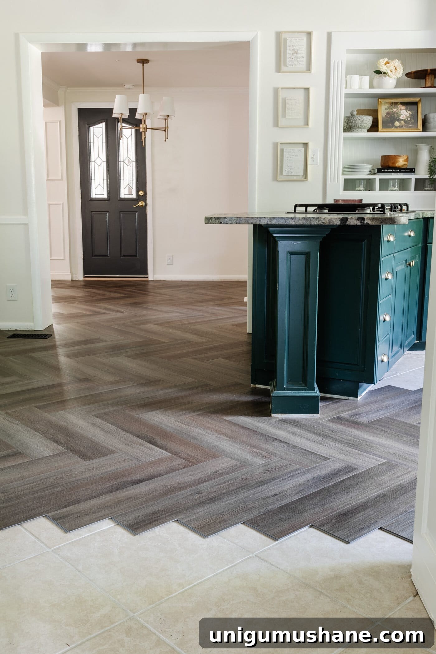 herringbone LVP floating floor over tile in a kitchen with white and green cabinets