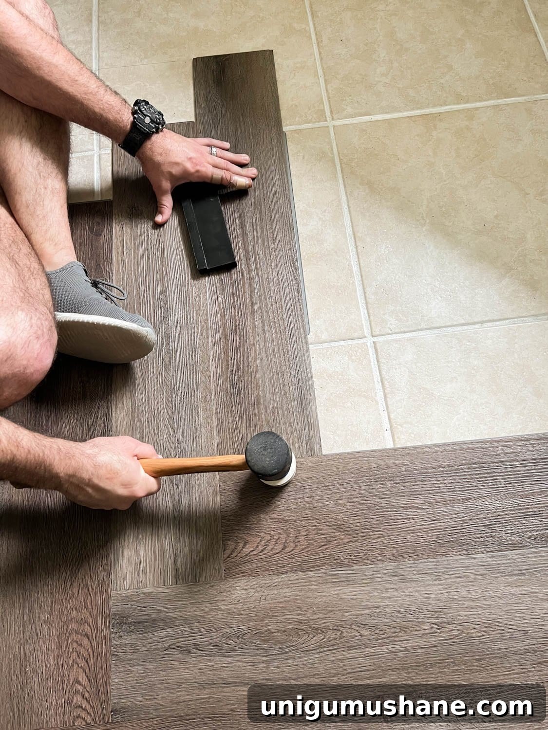 installing herringbone LVP floating floor over tile with mallet on seams to click into place