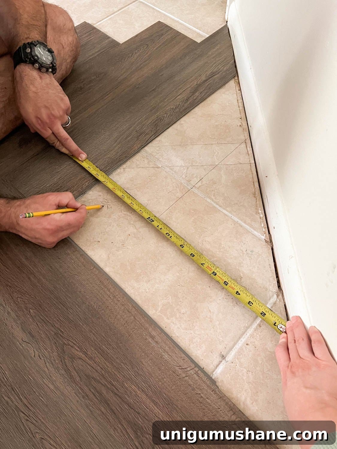 marking measurements to cut flooring pieces to fit against wall