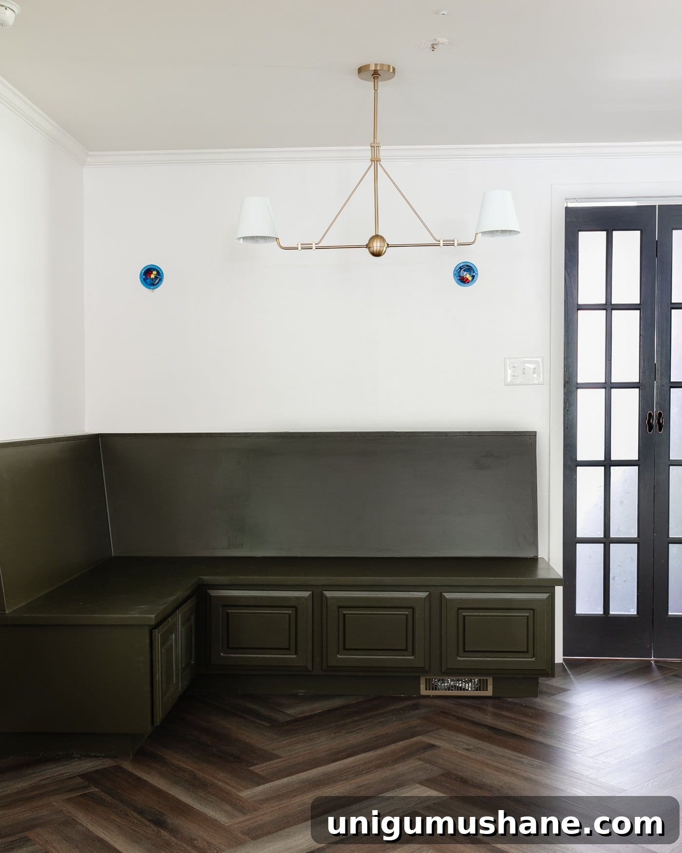 Transform Corner Banquette and Redirect Under Cabinet Air Vents 18 corner banquette in a breakfast nook with linear chandelier, herringbone floor, and French door