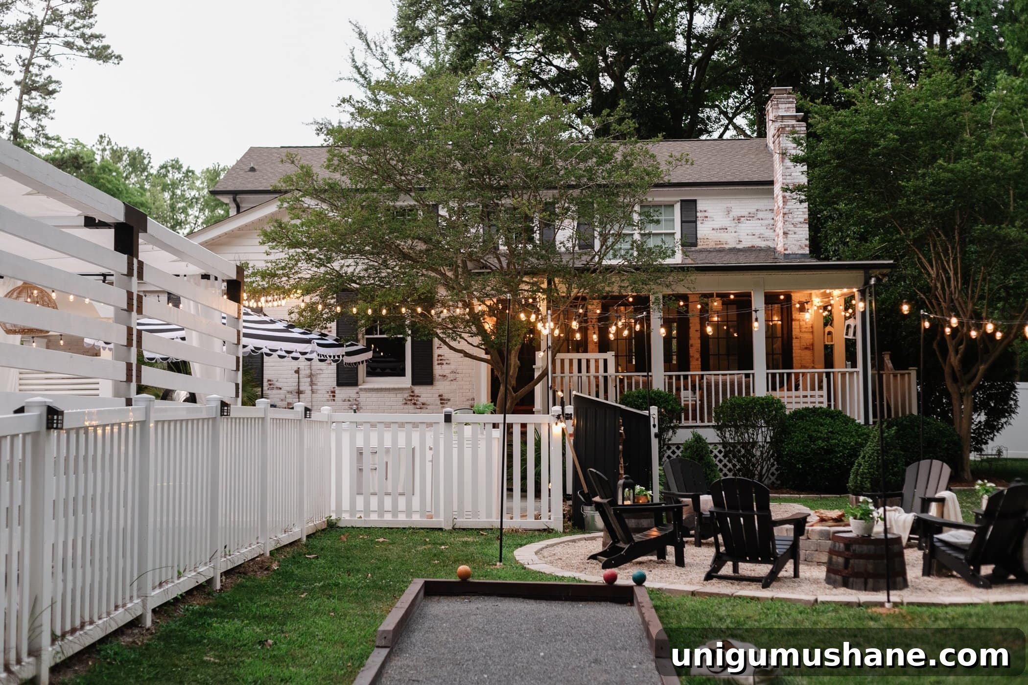 Backyard Lighting Ideas You Can Install Yourself 16 backyard with string lights, a bocce ball court, and fire pit with black Adirondack chairs