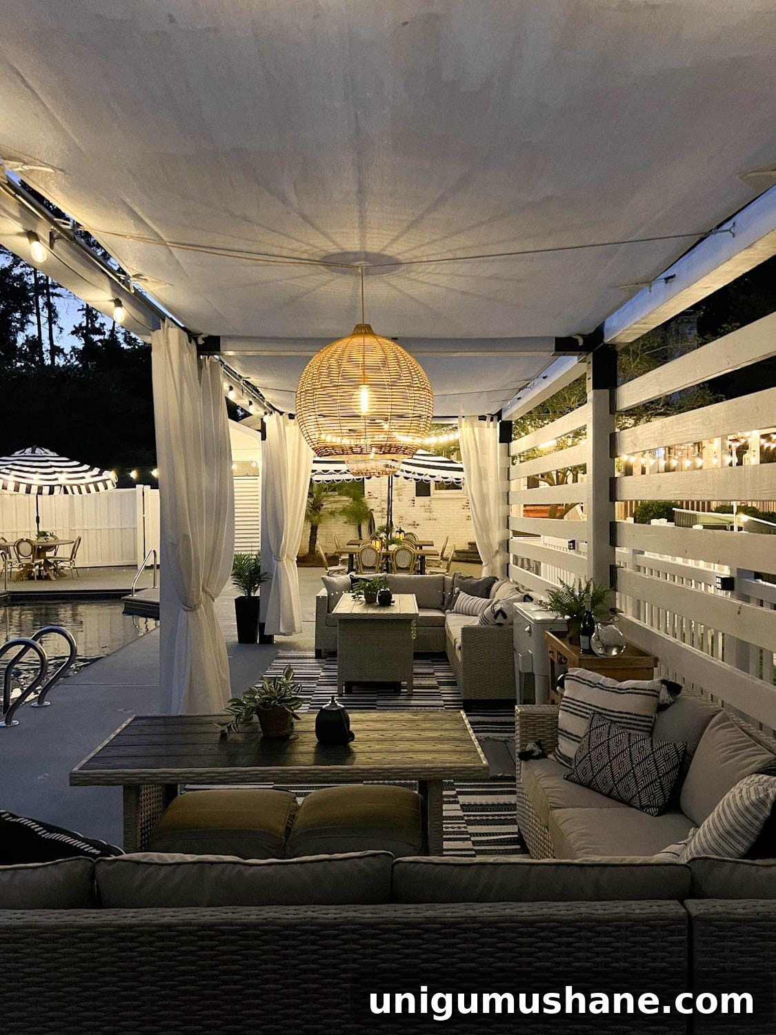 Backyard Lighting Ideas You Can Install Yourself 7 a pergola cabana with patio dining furniture, solar pendant lights, and string lights beside a pool at night