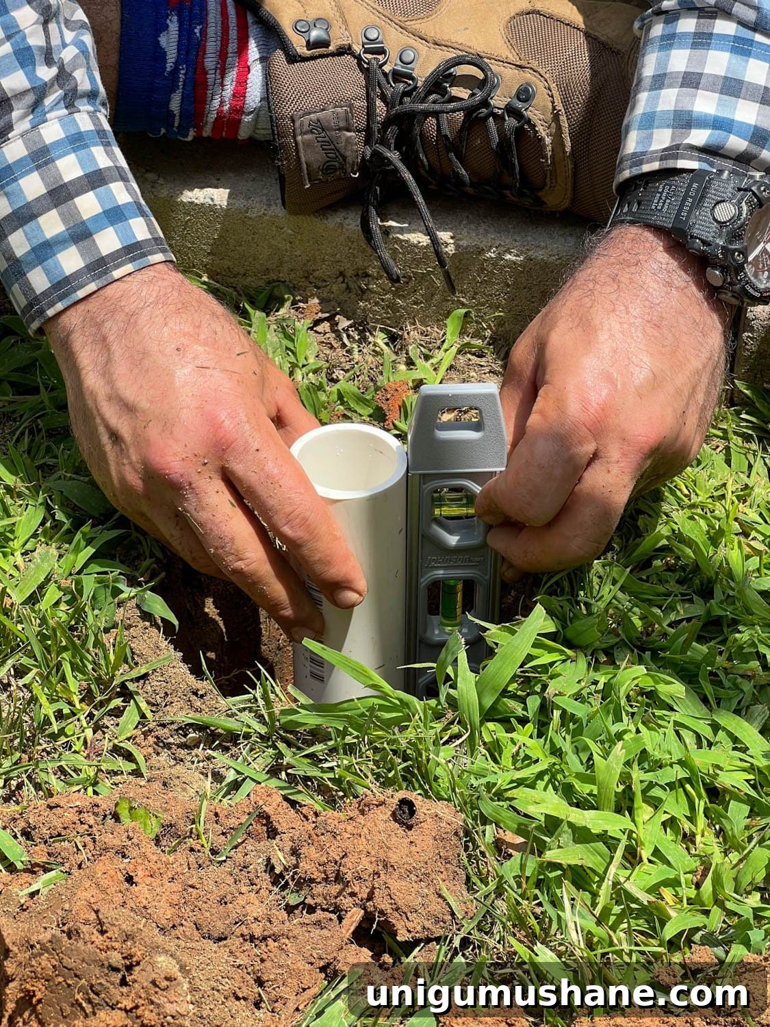 How to Hang Outdoor String Lights Anywhere in Your Backyard 15 checking to make sure PVC pipe is level in 2 foot deep hole
