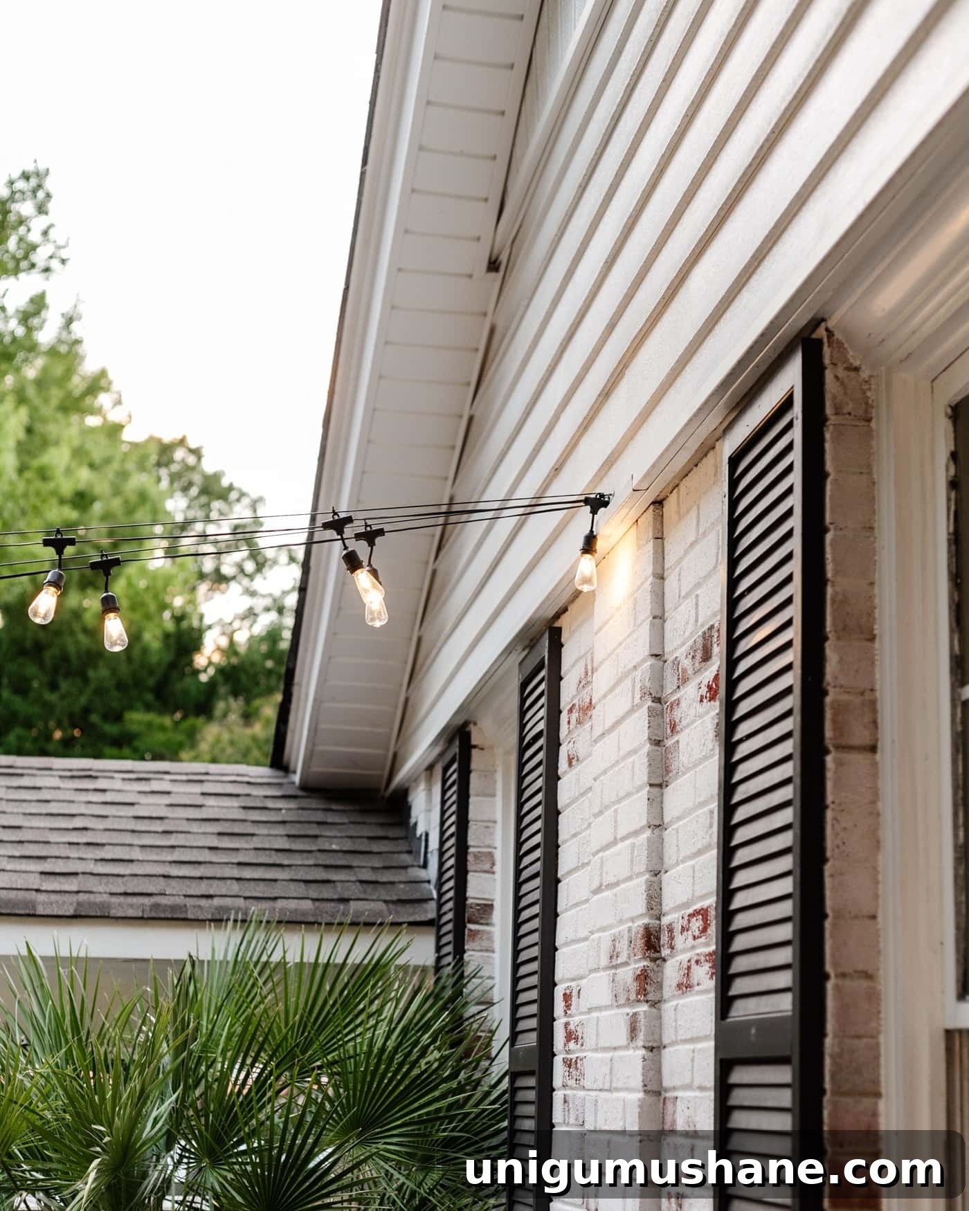How to Hang Outdoor String Lights Anywhere in Your Backyard 4 string lights hanging from a hook on the side of a brick house