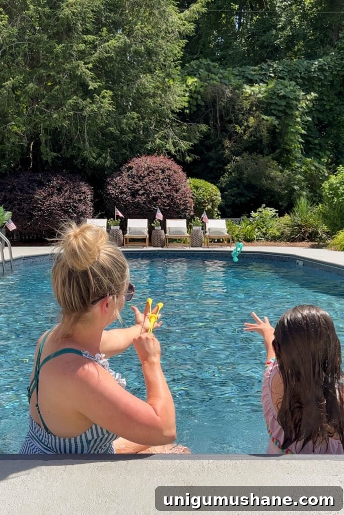 Must-Have Pool Toys for Kids and Adults This Summer 11 mother and daughter playing with slingshot dive toys beside a backyard swimming pool