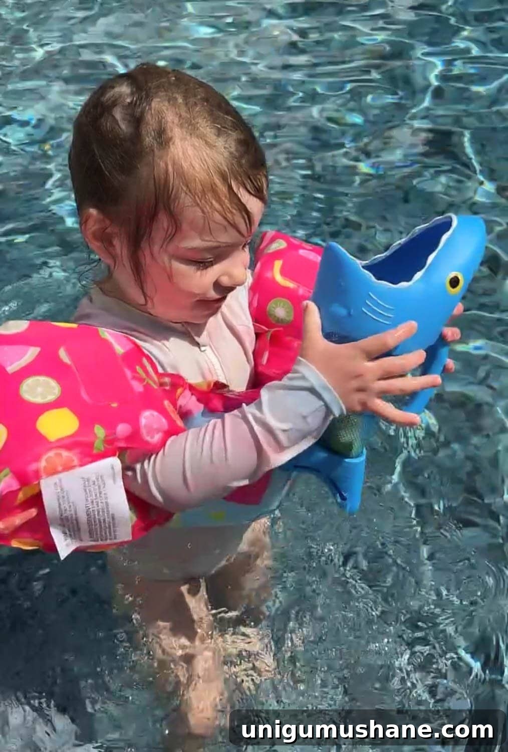 Must-Have Pool Toys for Kids and Adults This Summer 12 toddler girl playing with a shark pool toy game in the water