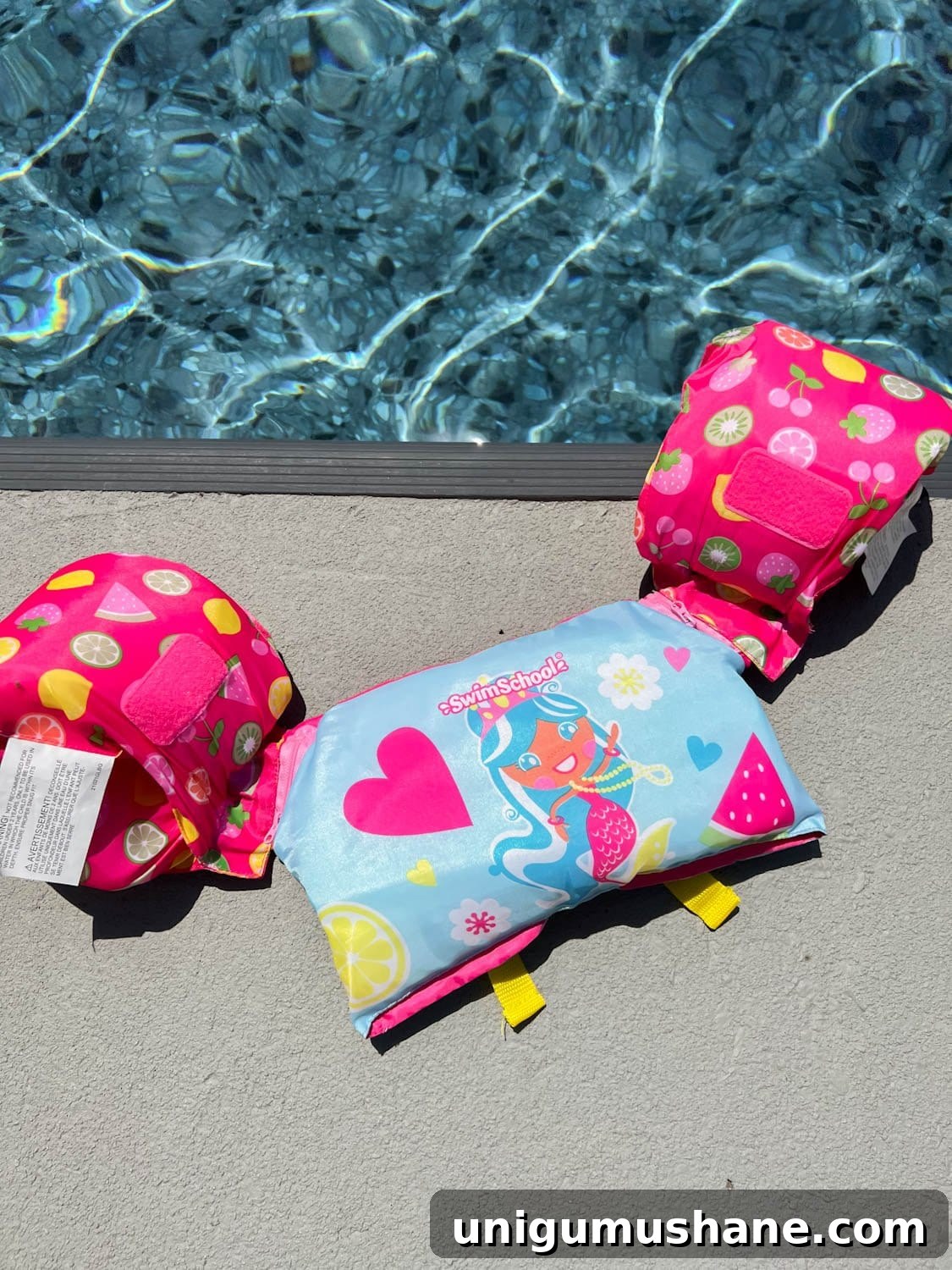 Must-Have Pool Toys for Kids and Adults This Summer 13 toddler swim vest on the ground on the side of a swimming pool