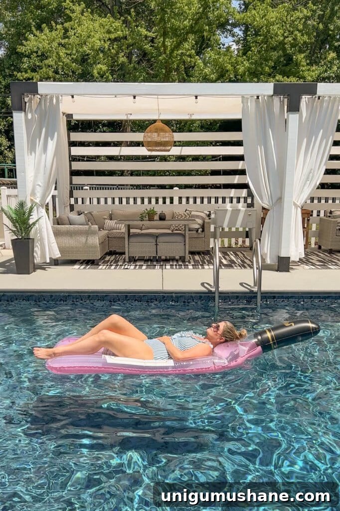Must-Have Pool Toys for Kids and Adults This Summer 19 woman lying on a wine bottle shaped pool flat in the water in front of a cabana