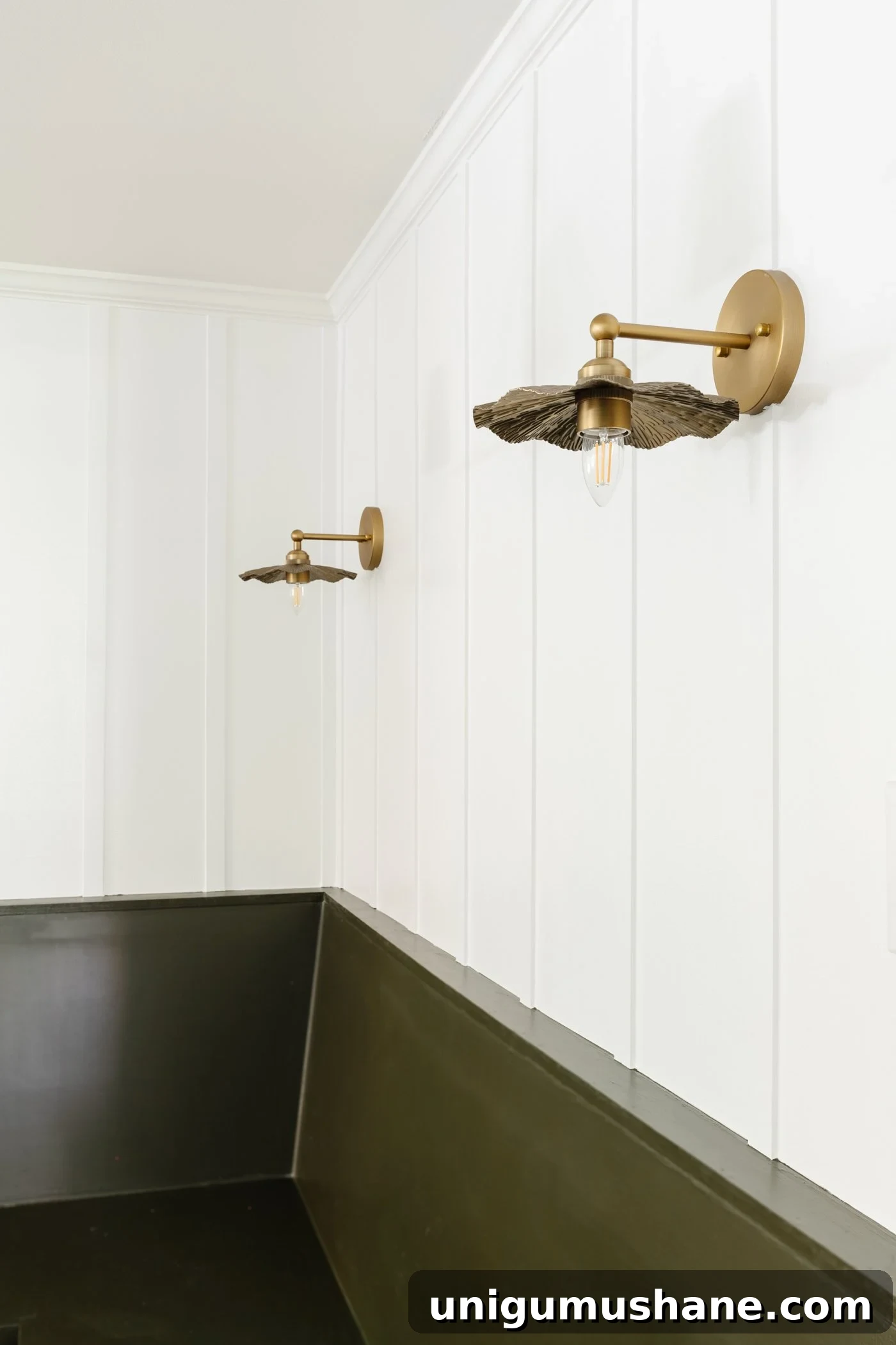 batten wall painted white with brass vintage style sconces and green banquette