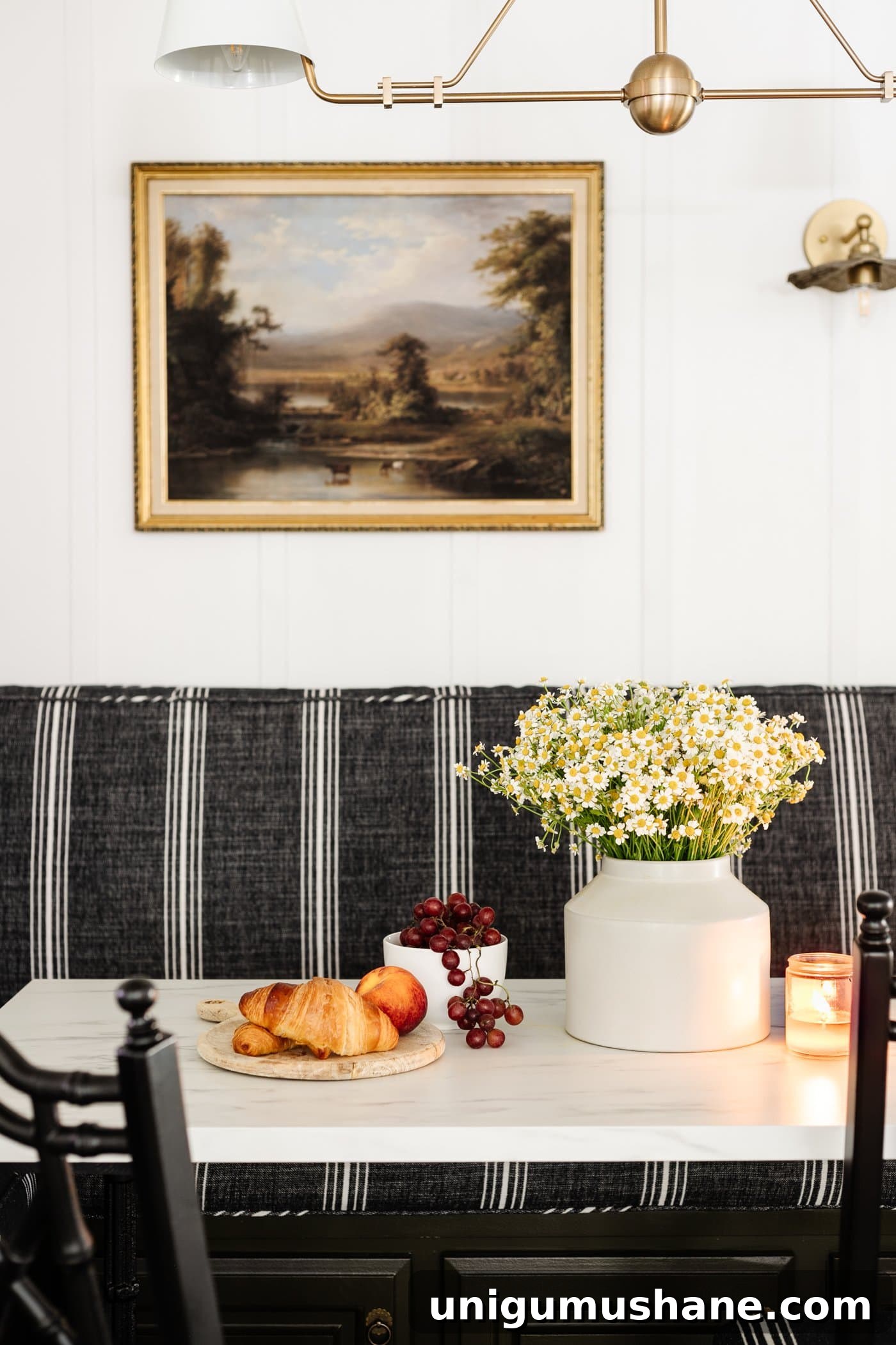 breakfast table decor - vase of daisies, wood cutting board with croissants, bowl of grapes, and candle