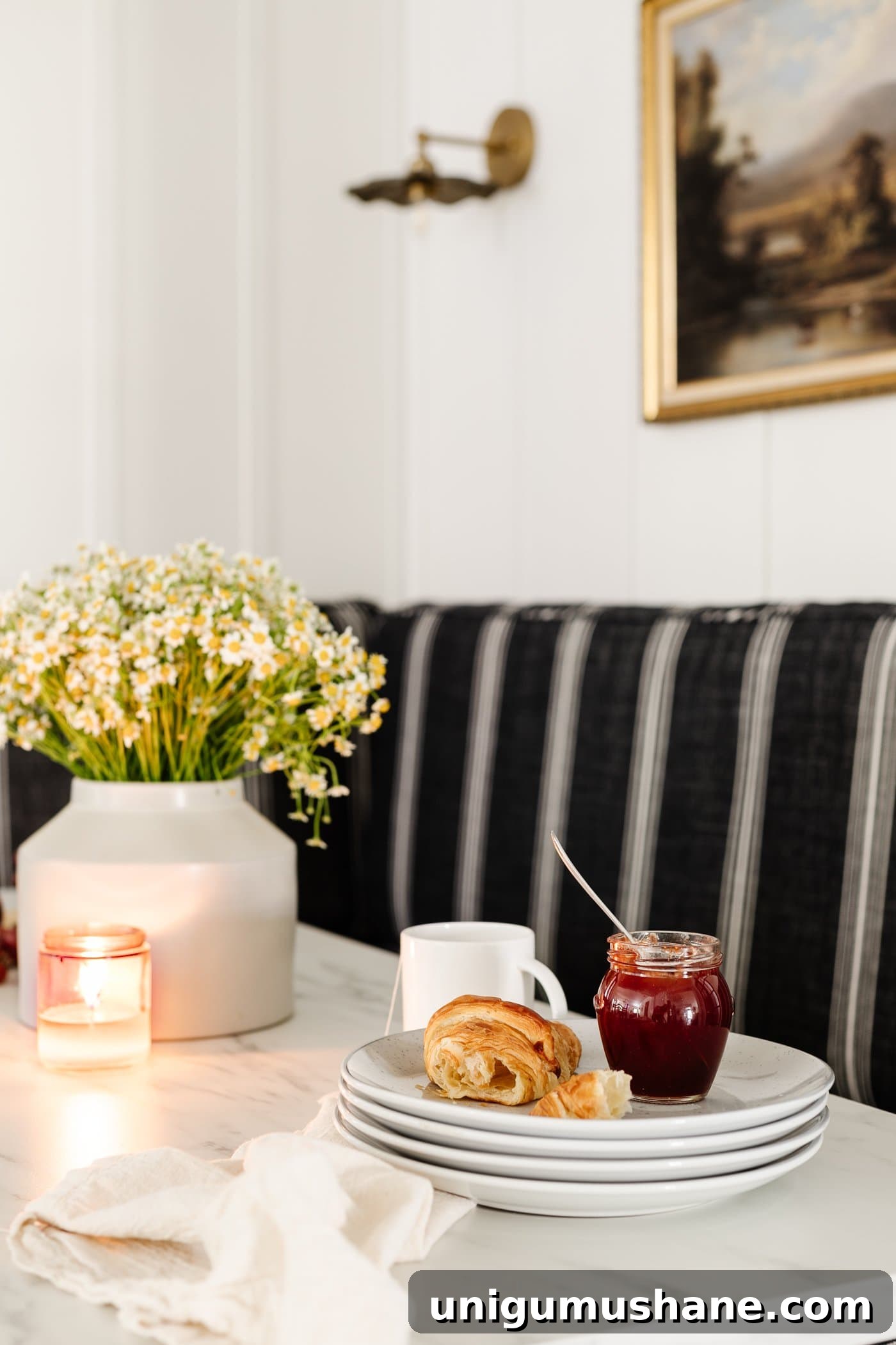 breakfast table decor - vase of daisies, wood cutting board with croissants, bowl of grapes, and candle