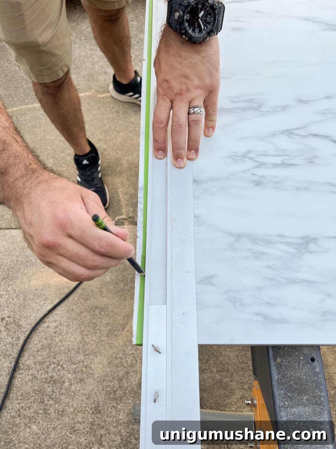 marking straight edge on masking tape on laminate faux marble countertop to be cut