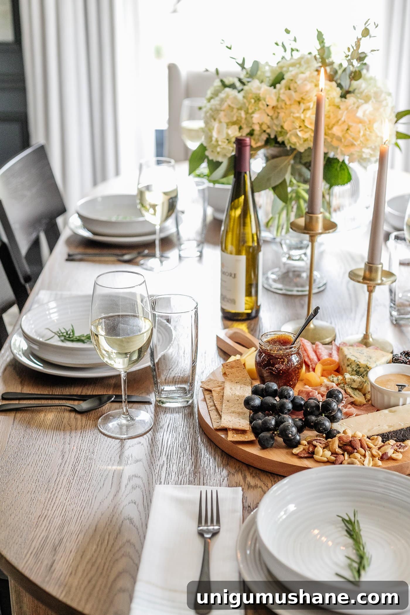How to Set an Elegant Dinner Table for Any Occasion 17 dinner table decor with simple place setting, wine glasses, charcuterie board, candlesticks, and vase of flowers