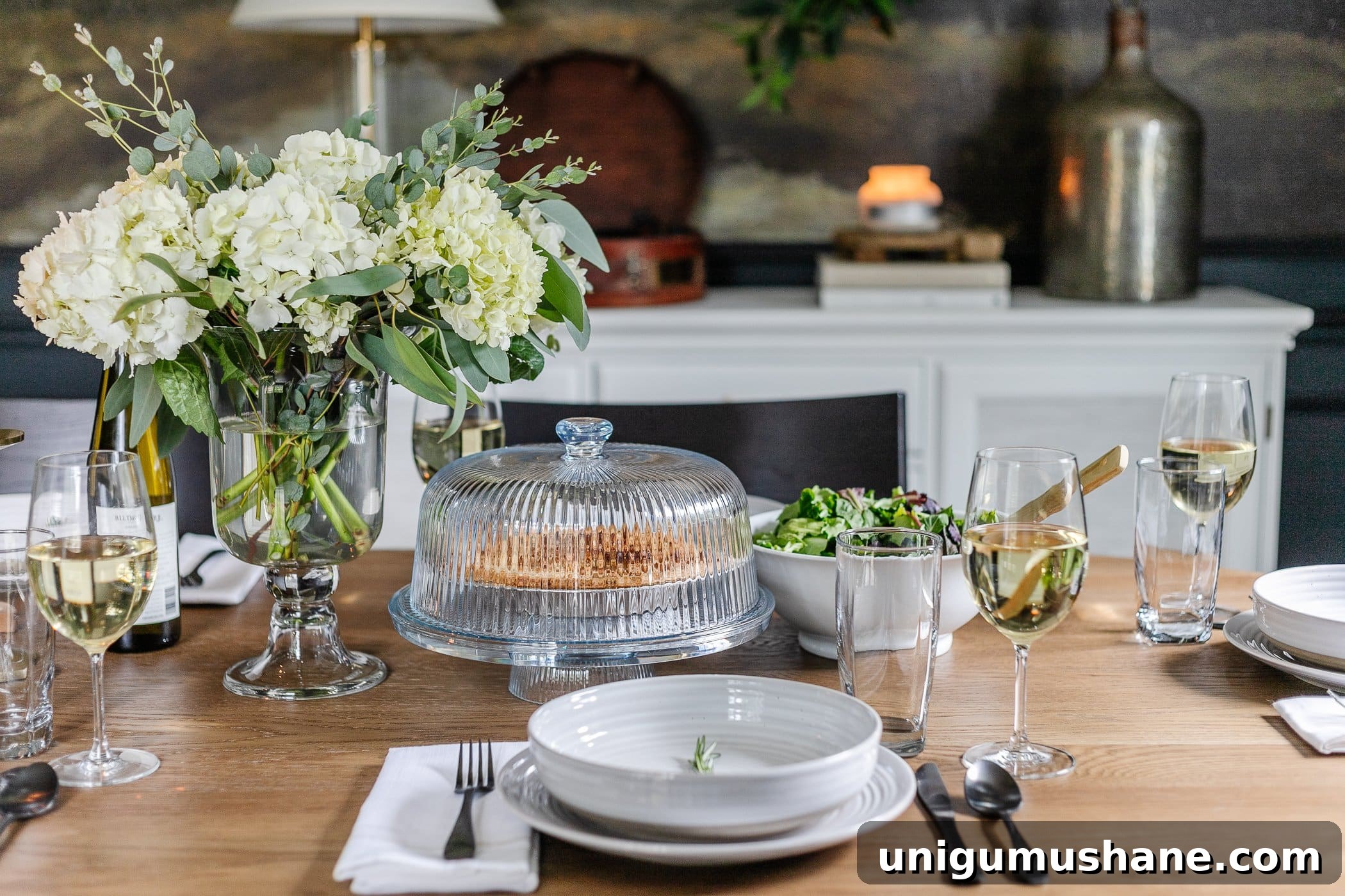 How to Set an Elegant Dinner Table for Any Occasion 8 vase of hydrangeas, simple place setting of gray dishes and sprig of rosemary, cake dome, and serving bowl of salad