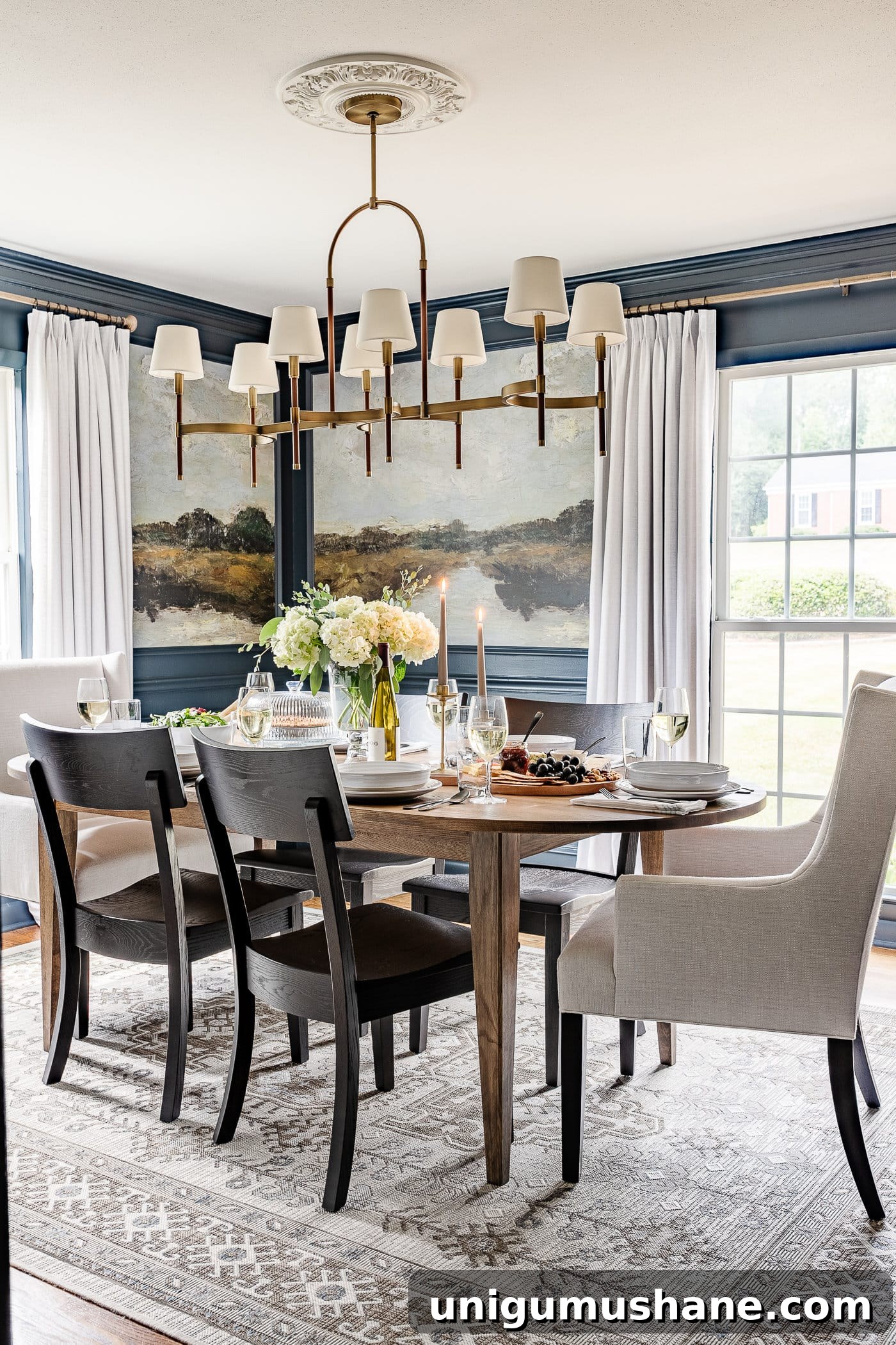 5-Year Home Transformation: Before and After Tour 13 navy blue dining room with mural walls in picture frame molding, linen curtains, shaded chandelier, wood oval dining table, linen head chairs, and black dining chairs