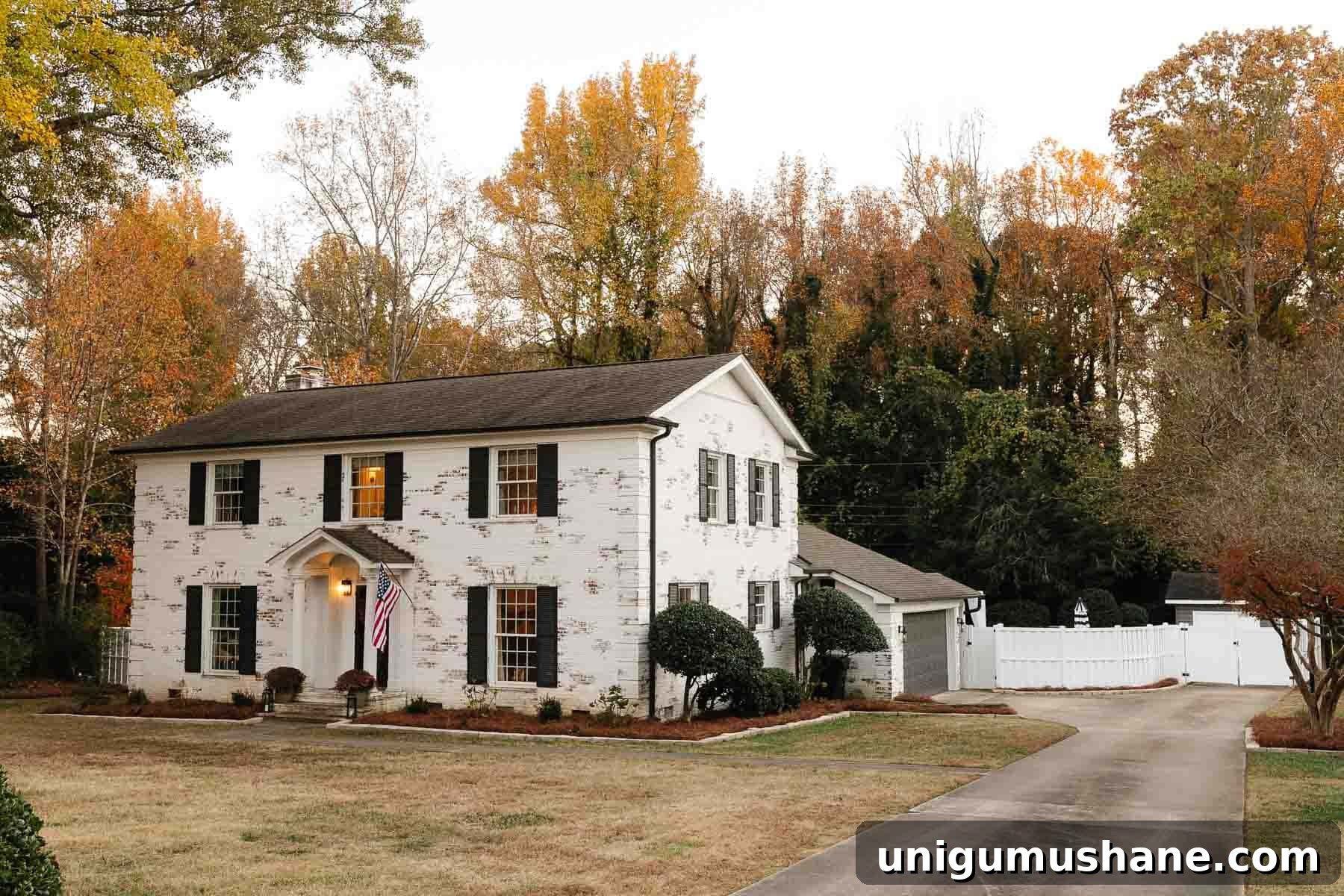 5-Year Home Transformation: Before and After Tour 4 white limewashed brick colonial house with black shutters and black doors and white vinyl fence