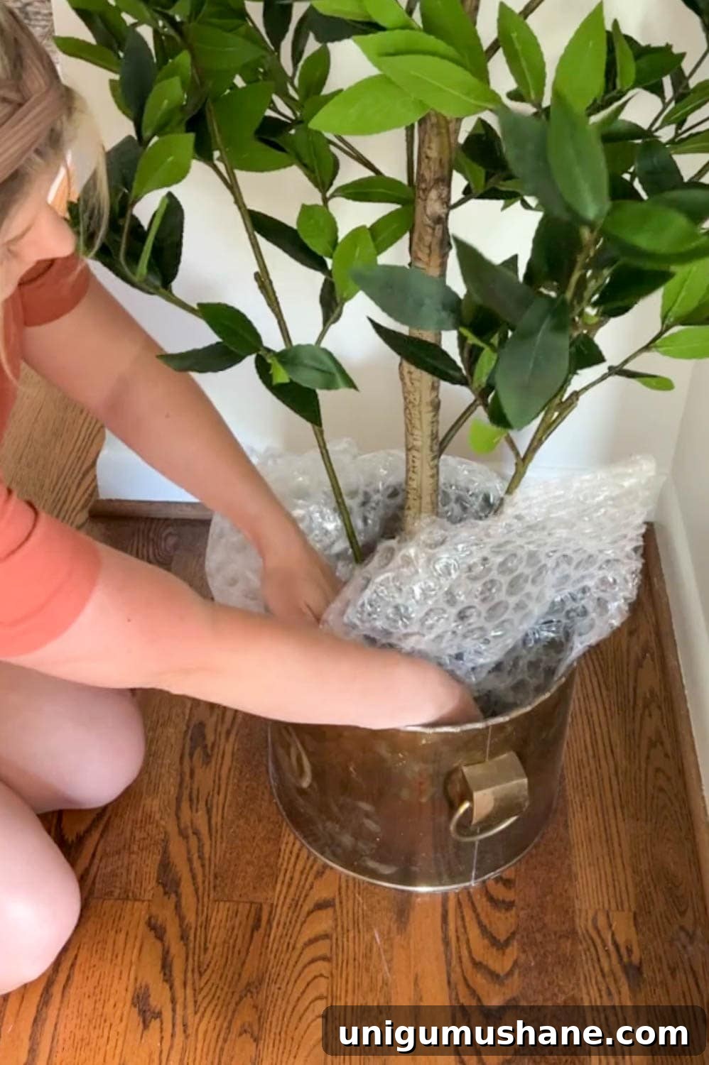Make a Fake Tree Look Real: Lifelike Styling Tips 5 stuffing a thrifted brass planter at the base of an artificial tree