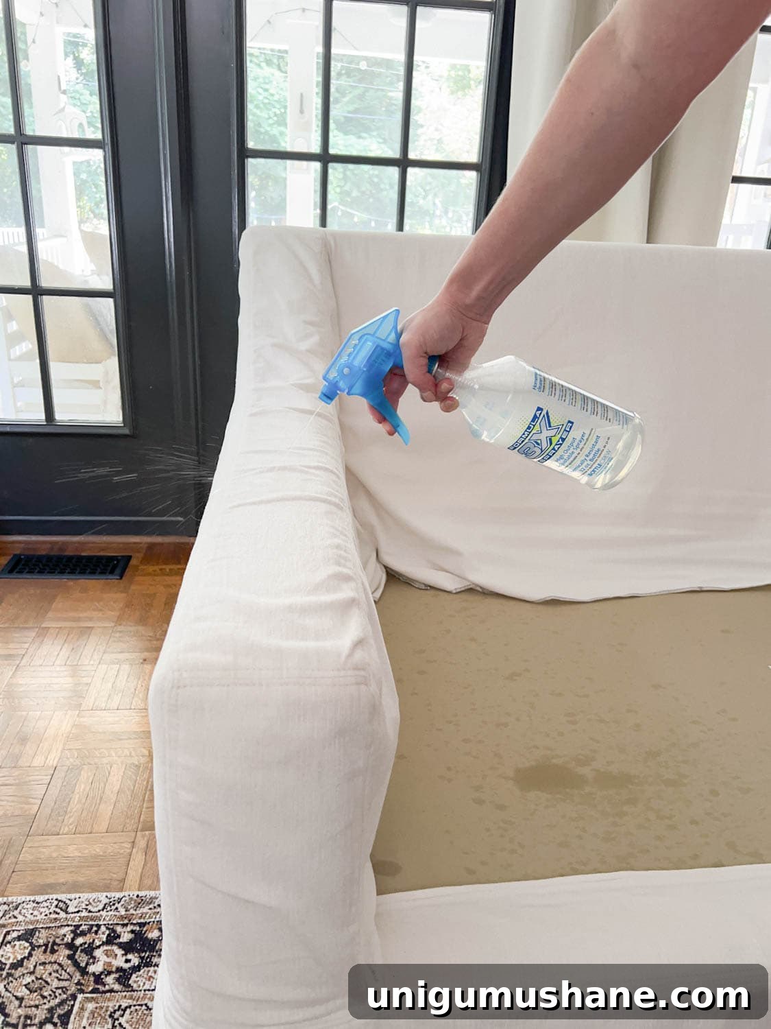 spraying DIY couch cleaner onto sofa to clean off dirt and grime