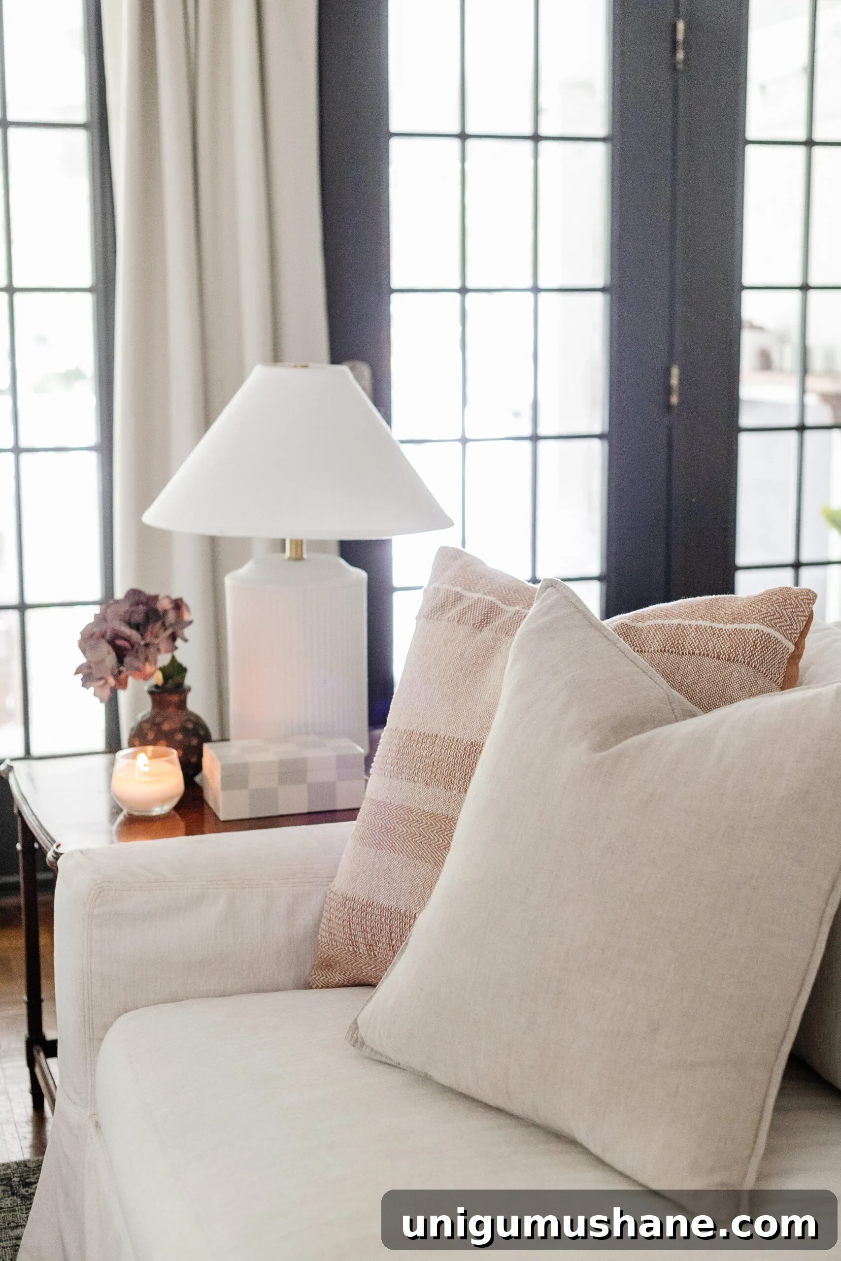 Budget Fall Living Room Decor Ideas That Save Time 9 neutral throw pillows on a white couch with subtle end table decor and lamp