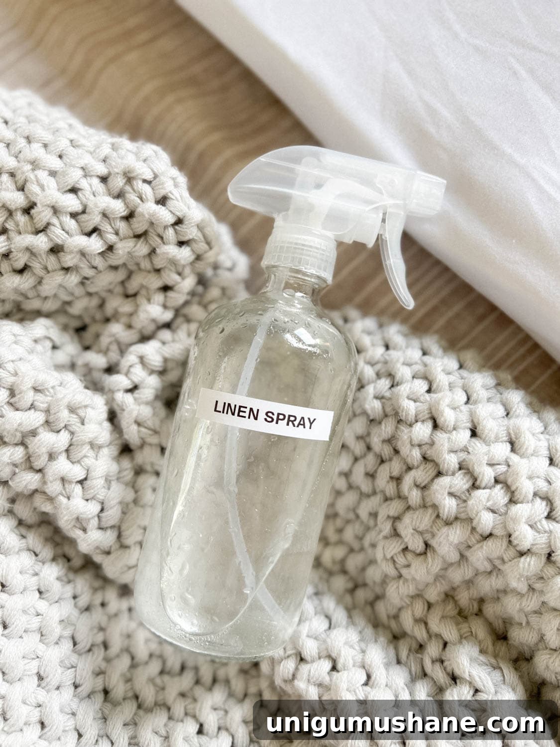 16 Natural Home Fragrance Hacks for a Fresh Smelling House 11 DIY linen spray in a glass spray bottle on bedding