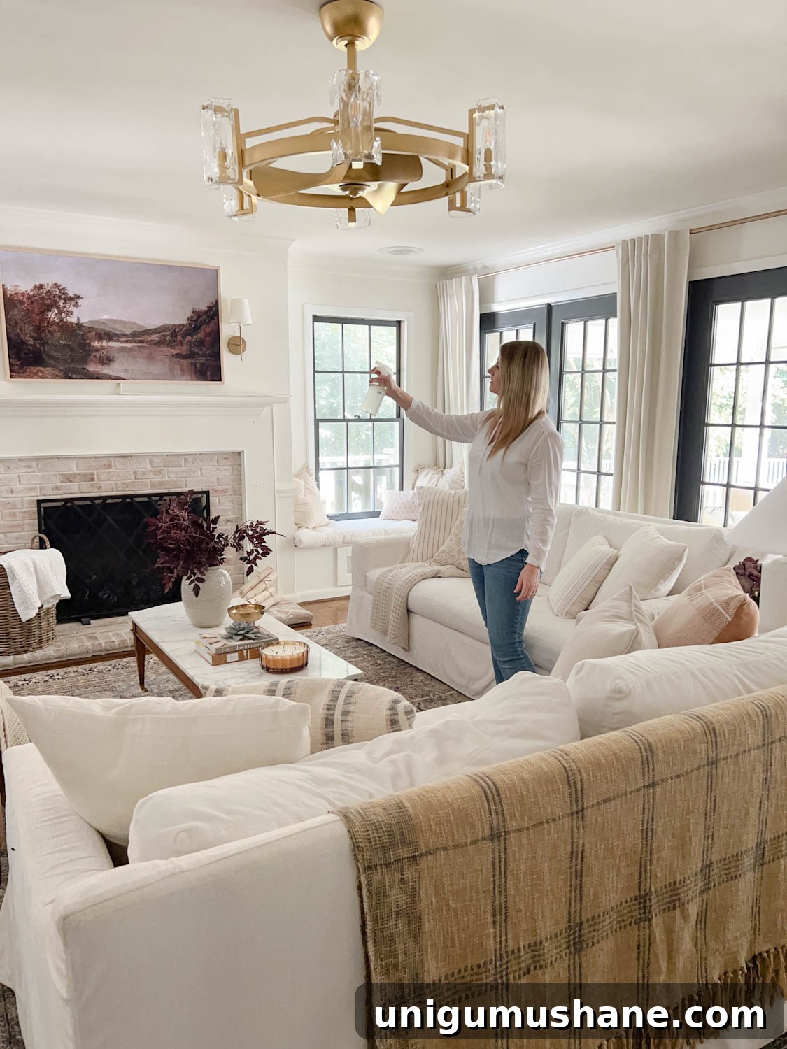 16 Natural Home Fragrance Hacks for a Fresh Smelling House 9 spritzing room spray in a living room