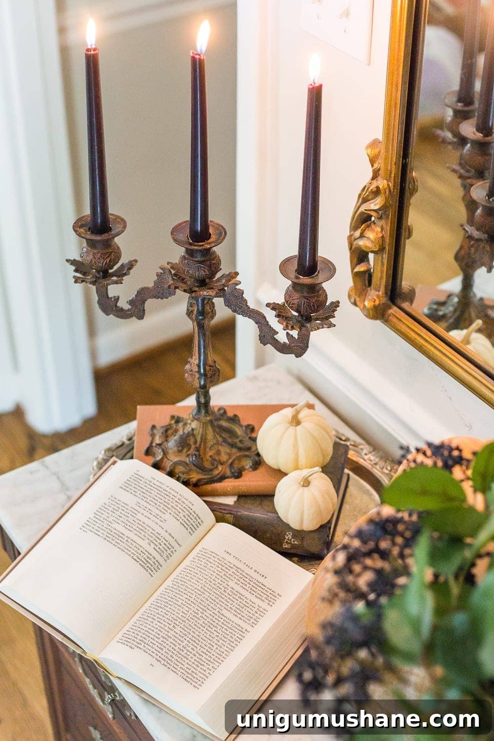 iron candelabra with black candles, silver tray, mini pumpkins, and old books for a vintage Halloween look