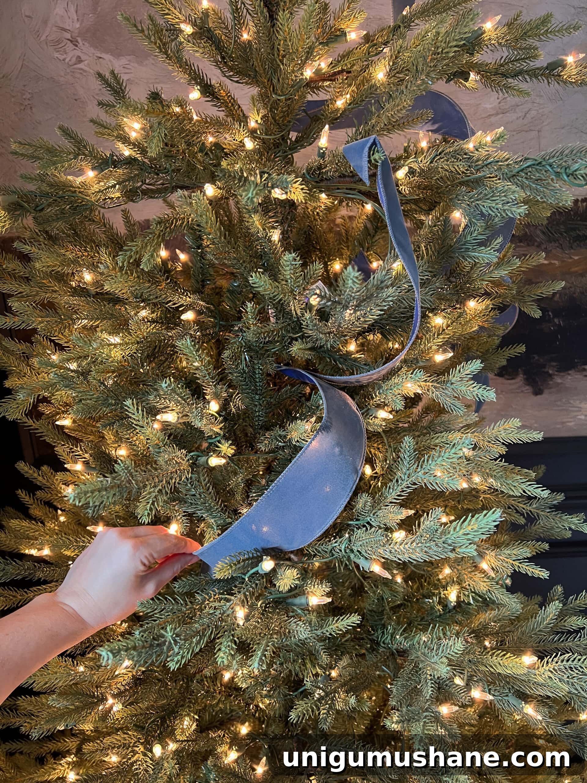 How to Add Ribbon Decorations to Your Christmas Tree 8 tucking ribbon piece between branches