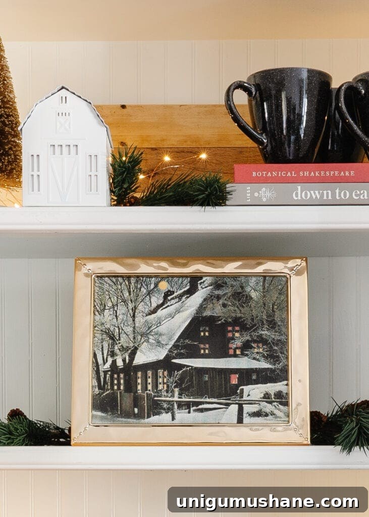 18 Christmas Wall Decor Ideas with Holiday Art Printables 10 Christmas art printable of a snow cabin in a picture frame on a kitchen shelf