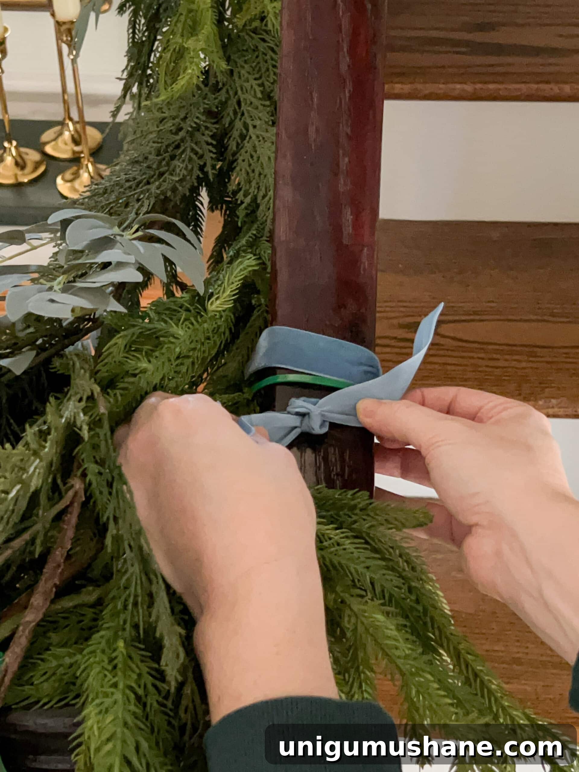 adding ribbon to cover zip ties on staircase garland
