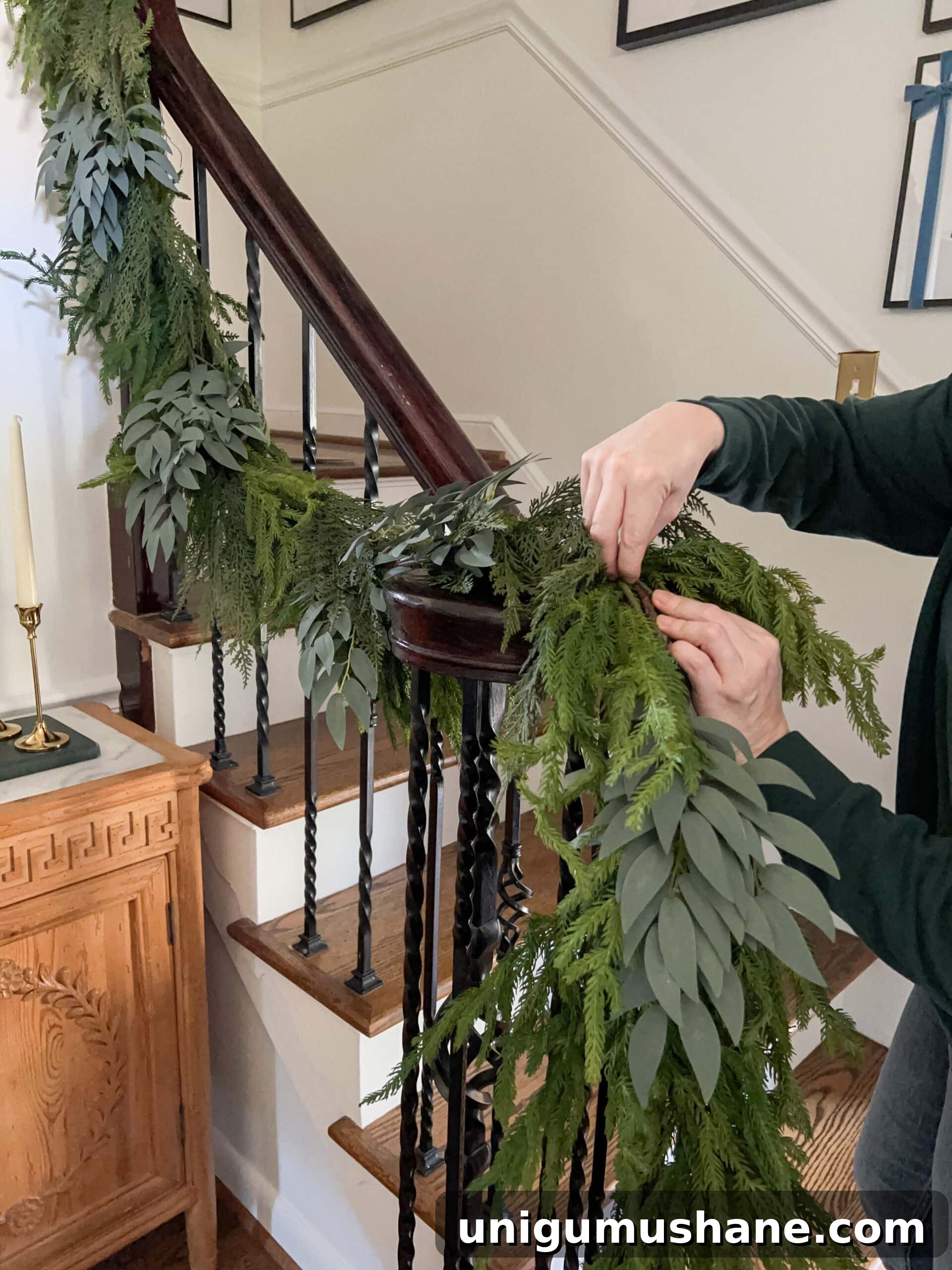 mixing leafy stems into artificial garland to make it look real
