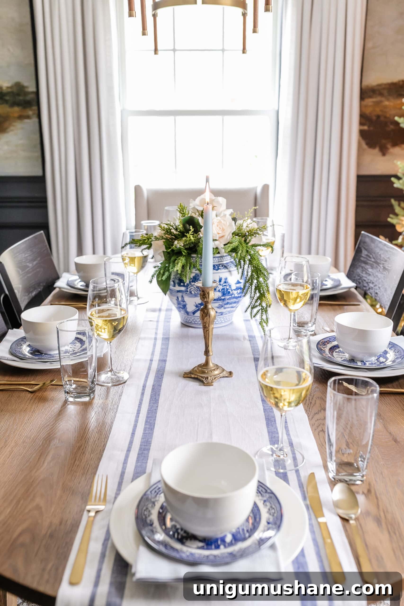 white and blue Christmas dinner table decor with candles, centerpiece, linens, and dinnerware