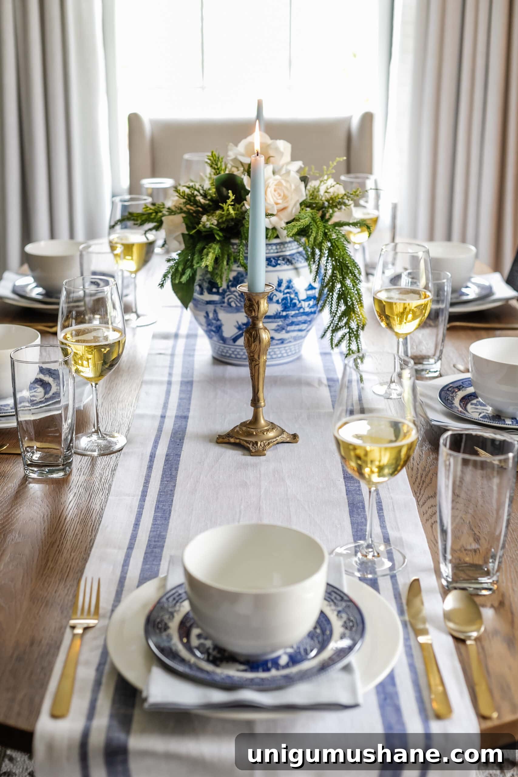 white and blue Christmas dinner table with blue striped runner and blue candles