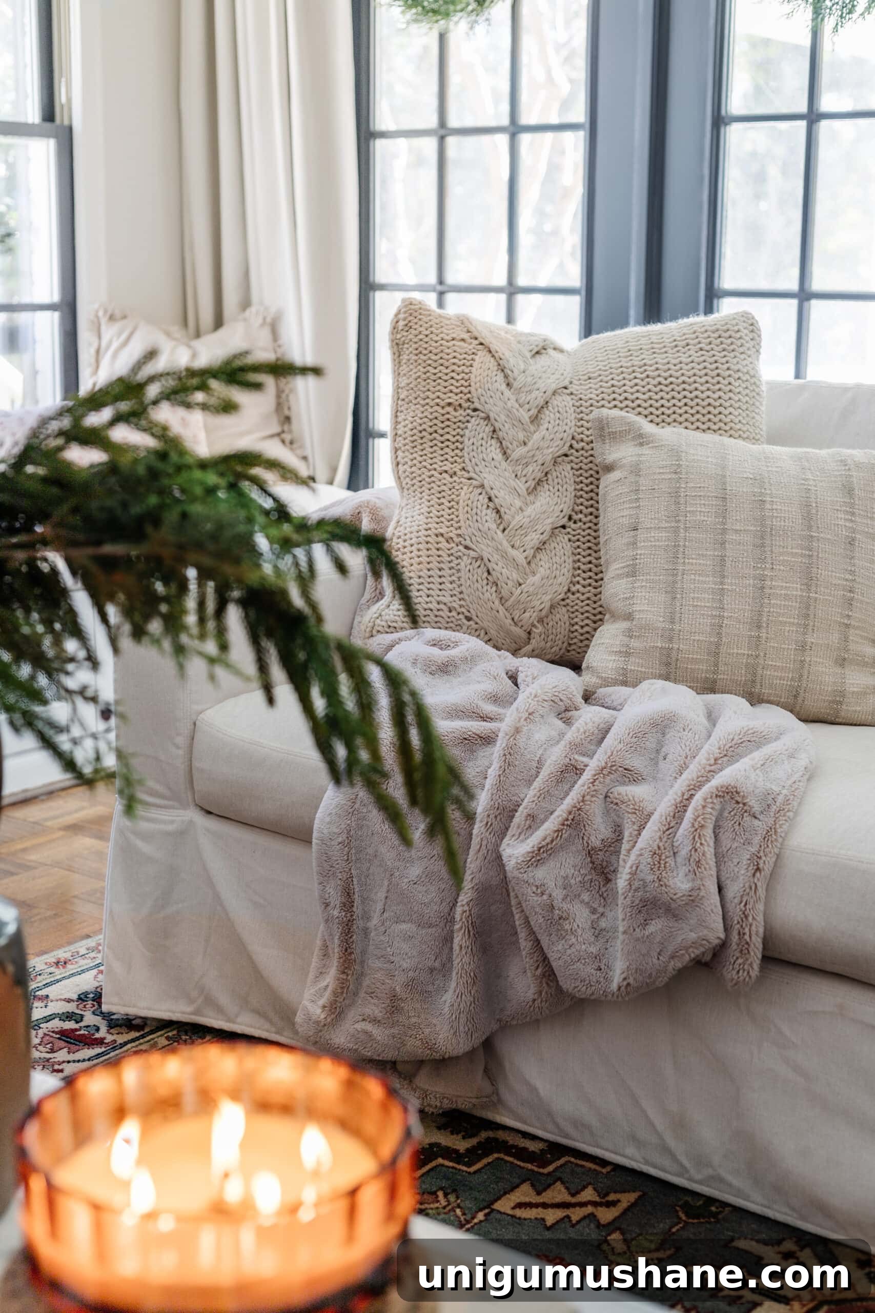 16 Cozy January Home Decor Ideas to Warm Your Home 2 winter home decor in a living room with faux fur blanket, knit pillows, green branches, and candles