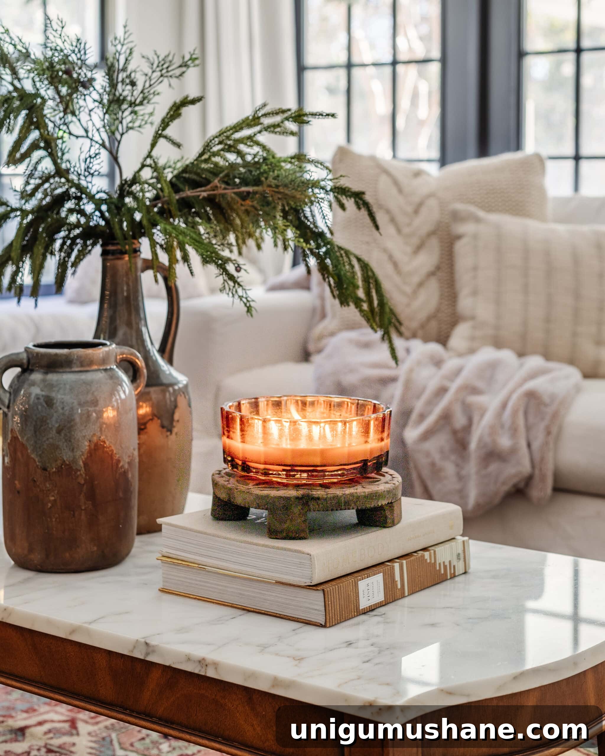 16 Cozy January Home Decor Ideas to Warm Your Home 4 candle, books, and vase with winter branches on a coffee table for January decor