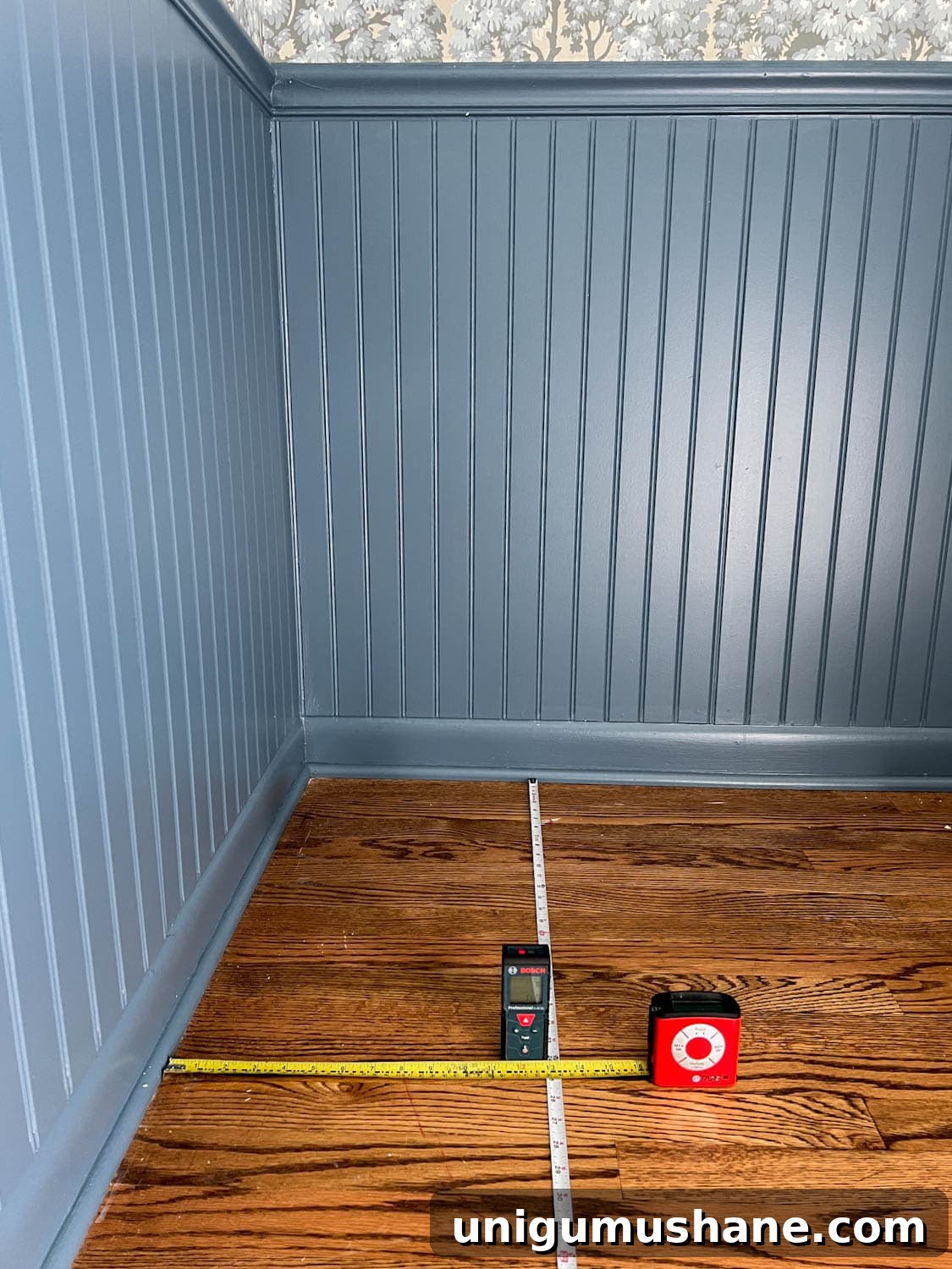 measuring and marking a block print pattern wallpaper on a ceiling using two tape measures and a laser