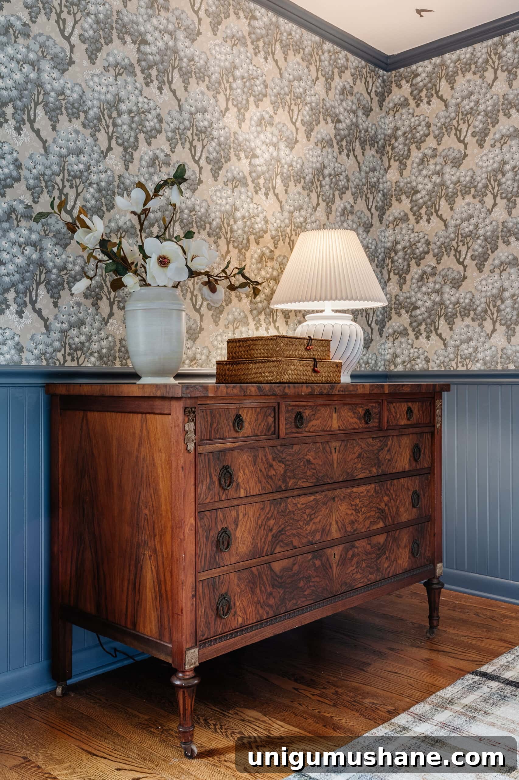 Burl Wood Furniture for Every Budget: Refinished Burl Dresser 6 burl wood dresser styled with vase of flowers woven basket boxes and lamp in a bedroom with blue vintage wallpaper
