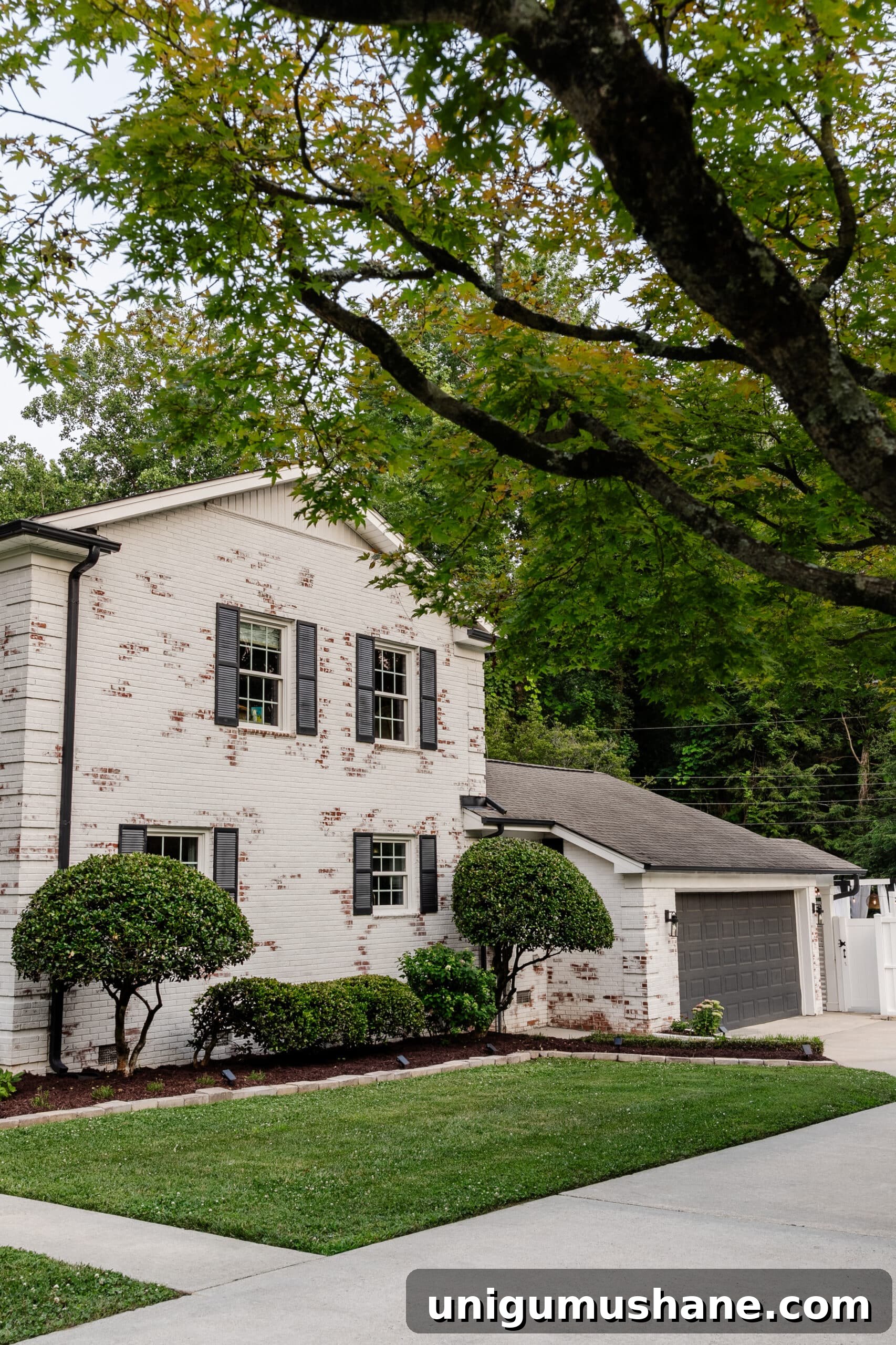 Limewashed Brick Cleaning and Maintenance Guide 18 white limewashed brick with black gutters, black shutters, and black painted garage door
