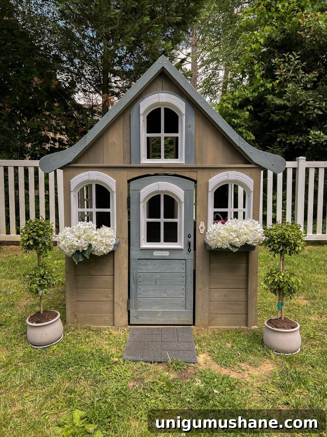 8 Side Yard Play Area Ideas and Trampoline Decor Tips 11 wooden outdoor playhouse with white flowers and topiaries