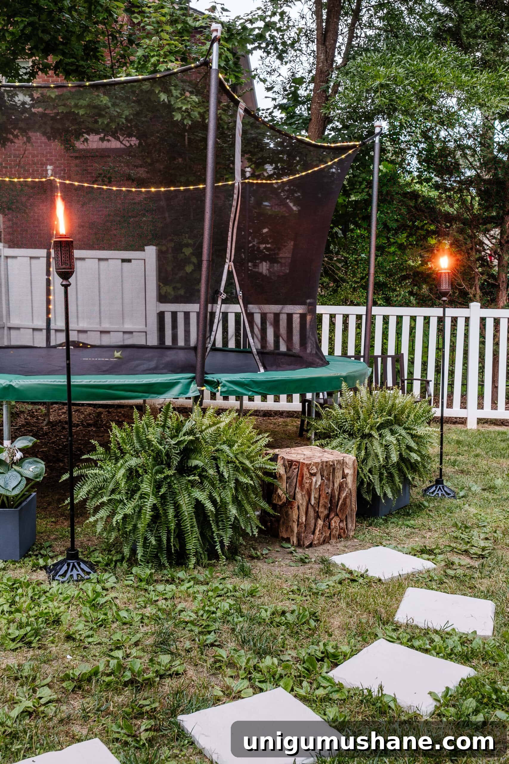 8 Side Yard Play Area Ideas and Trampoline Decor Tips 7 stepping stones leading to outdoor trampoline with tree stump trampoline ladder, ferns, and tiki torches