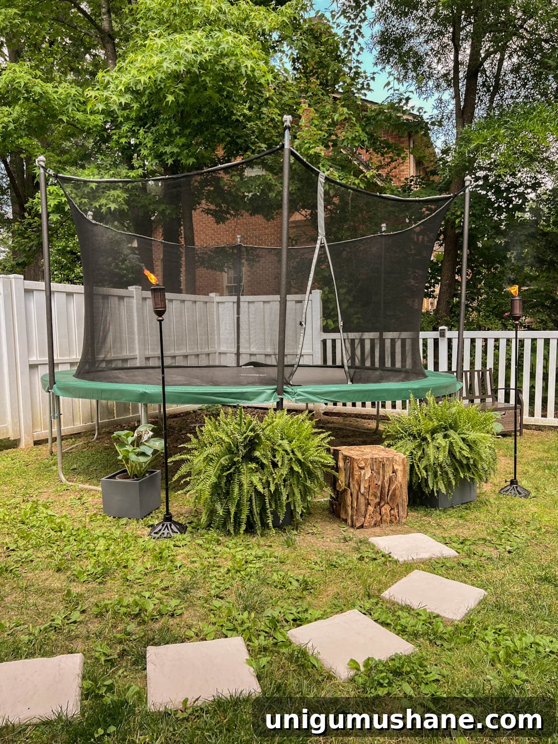 8 Side Yard Play Area Ideas and Trampoline Decor Tips 9 stepping stones leading to outdoor trampoline with tree stump trampoline ladder, ferns, and tiki torches